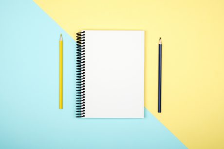 Top view of open spiral blank notebook on colorful desk background
