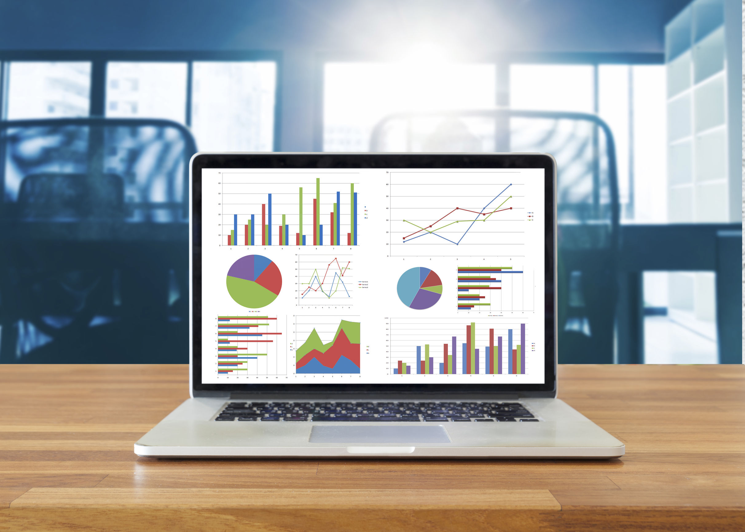 Laptop on wooden table showing charts and graph against office background ,Analysis Business Accounting, Statistics Concept.