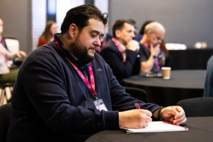 A man at the UCISA conference writing notes.